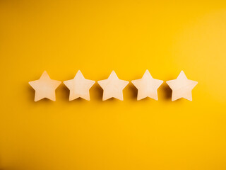Five wooden stars ratings, on yellow background. 5 points, highest level of excellence quality or satisfaction, customer evaluation, business marketing concept.