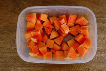 Plastic container full of cut off fresh papaya fruit