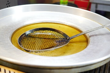 Frying pan with a skimmer tool in a street food vendor's kitchen