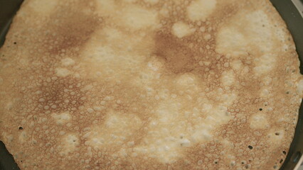Golden Brown Pancake Cooking on a Skillet with some Butter and Maple Syrup on Top