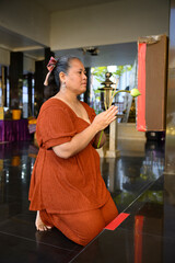 Buddhist woman praying with incense and lotus flower in a temple
