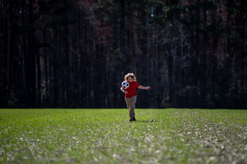 A child play soccer outdoors. A child kicks soccer ball. The kids sport. Child football player runs toward goal. Child kicking the soccer ball. A sporty children. Kids playing soccer on the field.