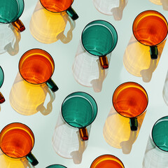 Orange and green glowing glass cups on teal background, artistic light reflections and shadow in...