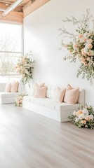 A white sofa with peach pillows sits in front of a white wall adorned with floral arrangements