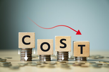 Concept of cost reduction in business finance with wooden blocks spelling COST placed on descending...