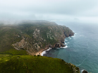 High-angle drone view of a hidden cove surrounded by steep green slopes