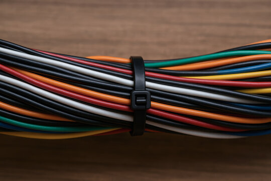 Bundle of multicolored electrical wires secured with black zip tie represents essential power connections in industrial plant setting