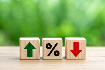 Interest rate or financial market fluctuation concept shown with wooden blocks featuring percentage, up, and down arrow symbols on a natural background.