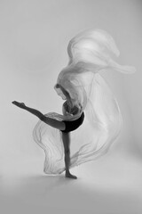 A girl in a swimsuit and a dress shows beautiful athletic elements on a white background. Ballet, rhythmic gymnastics, fabric, aesthetics, grace