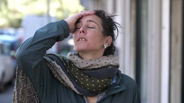 A brunette woman reacts with visible irritation after realizing she forgot to bring something essential, touching her head in frustration