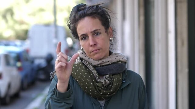 A brunette woman expresses with her fingers that something is minimal or insignificant, slightly amused by its size