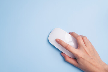 Hand using white minimalist mouse isolated on blue background.