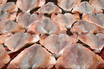 Fresh fish fillets spread out on a drying rack to preserve and enhance flavors.