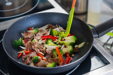 Beef and vegetables are fried in a frying pan. 