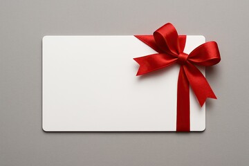 Clean Blank White Gift Card Presentation with Bright Red Ribbon Bow Isolated on Smooth Neutral Grey Backdrop