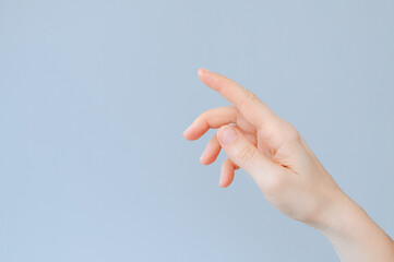 Woman's Hand Pointing with Index Finger on light blue background with copy space