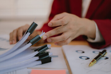 Asian businesswoman looking at finance, accounting, marketing and tax documents on desk in office.