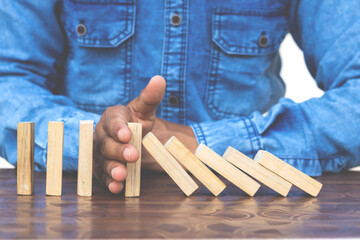 domino effect - hand of man stopping wooden block from falling