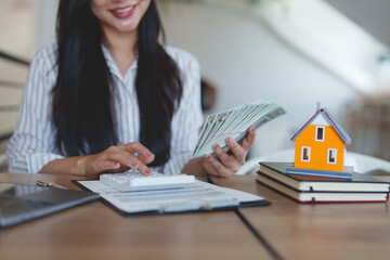 Real estate agent calculating mortgage costs holding us dollar banknotes