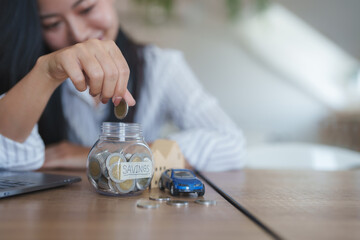 Woman saving money in jar for house and car purchase