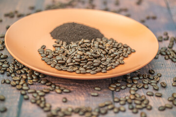 Fresh organic raw coffee beans and ground coffee on plate