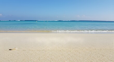 Serene Beach Scene: Sandy Shoreline Meets Turquoise Sea Under Bright Blue Sky, Tropical Paradise with Gentle Waves & Warm Sunlight