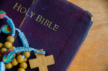 A Holy Bible resting with rosary and candlelight emphasizes devotion, prayer, and staying close to...
