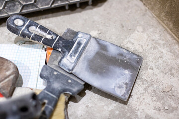 A spatula featuring a black handle is currently resting on a concrete surface