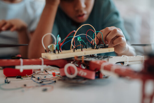 Young schoolboy assembling robotic kit, working with circuit board at home.