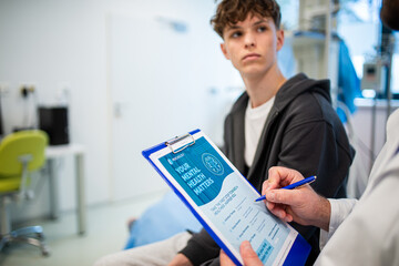 Close-up of doctor and teenage patient filling out mental health evaluation form.