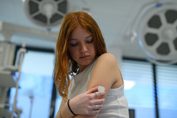 Teenage girl with diabetes checking CGM sensor during hospital visit.