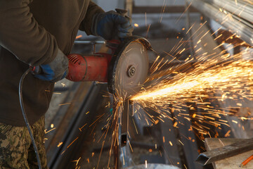 A man is using a power tool to cut metal
