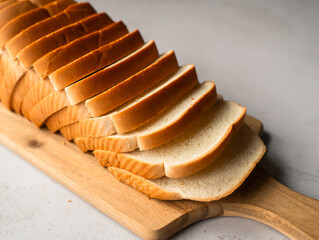 Close up of loaf of sliced white bread on wooden cutting board.