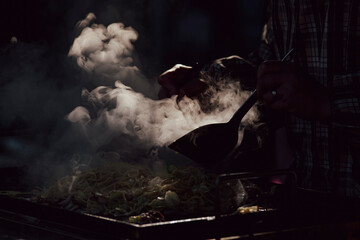 Moody light of steam rising from food cooking