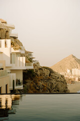 Sunlit cliffside villas overlooking Cabo San Lucas coastline and sea