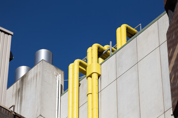 Yellow urban rooftop pipes on concrete industrial building