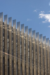 Modern building with metal vertical sunshades reflecting blue sky