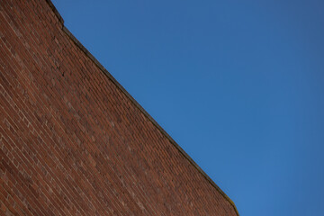 Diagonal red brick wall with blue sky forming geometric pattern