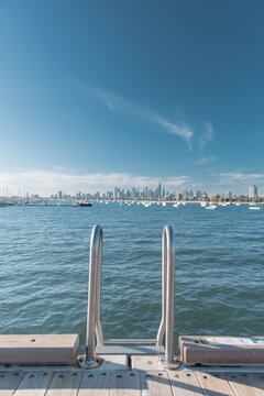 Metal Ladder on St Kilda pier with bay, boats and Melbourne Skyline