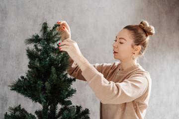A woman at home puts up an artificial Christmas tree