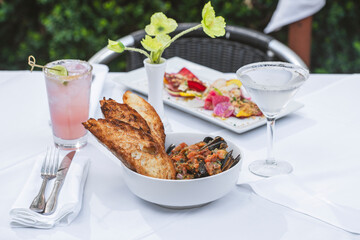 Cioppino and salad on white table with drinks