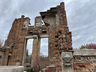 Tall brick ruins with ornate stonework and vines beneath cloudy skies