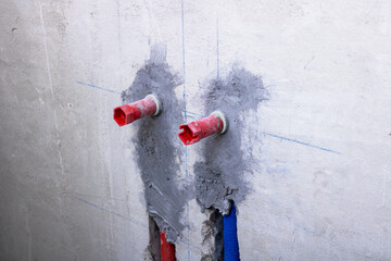 Two red pipes are currently connected to a sturdy concrete wall