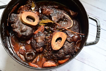Close-up of a rustic gourmet dish featuring slow-braised beef shank with bone (osso buco style),...