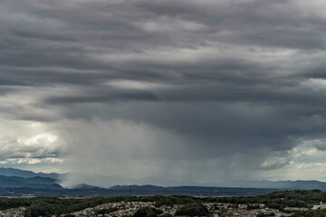 重い雨雲から丘の向こうに雨柱で土砂降りが降り注ぐ
