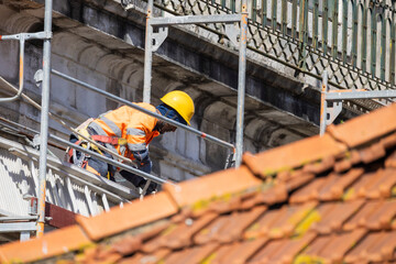 Construction worker restoring an old building facade using scaffolding