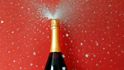 Champagne bottle with golden foil cap is erupting with sparkling wine, creating a festive atmosphere against a vibrant red background, symbolizing celebration and joy. Generative 4k video - Powered by Adobe