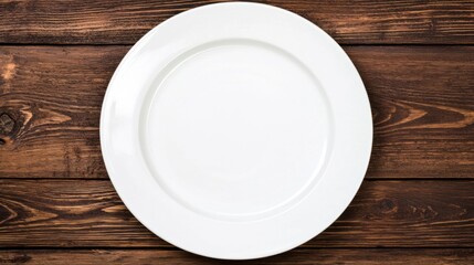 An empty white plate on a wooden table.