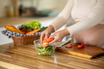 Pregnant Asian woman cooking healthy food at home