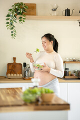 Pregnant Asian woman cooking healthy food at home